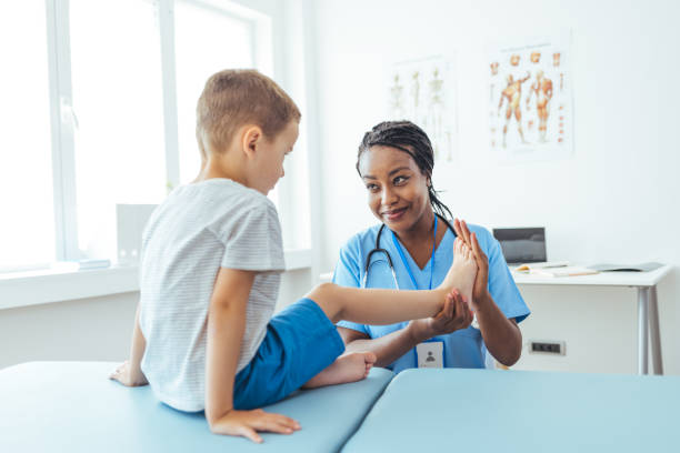 ortopedico femminile che esamina la condizione del piede del bambino piccolo in clinica - podiatrist foto e immagini stock