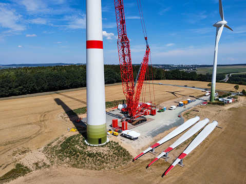 Offshore wind energy turbine supply vessel anchored and loading rotor in port harbor