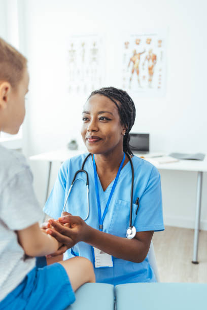istock Young boy sits facing a female doctor. 1415365542
