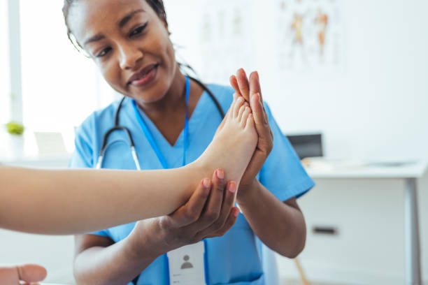 Female afro doctor examining childs feet in hospital. Female afro doctor examining childs feet in hospital. ankle stock pictures, royalty-free photos & images