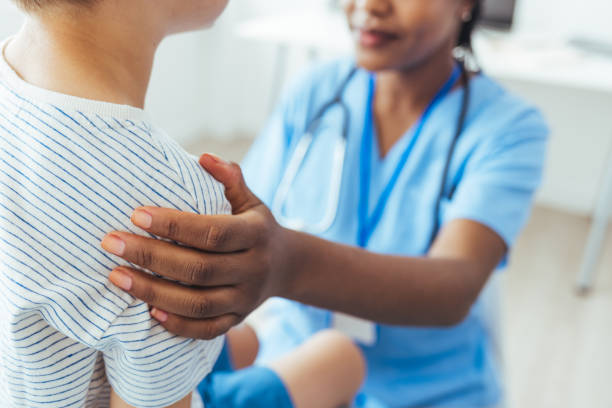 istock Confident nurse talks with boy patient 1415365641