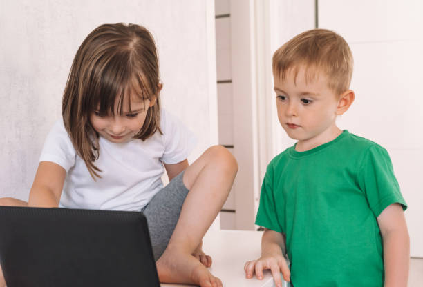 istock Boy and girl use laptop while sitting at home 1415367500