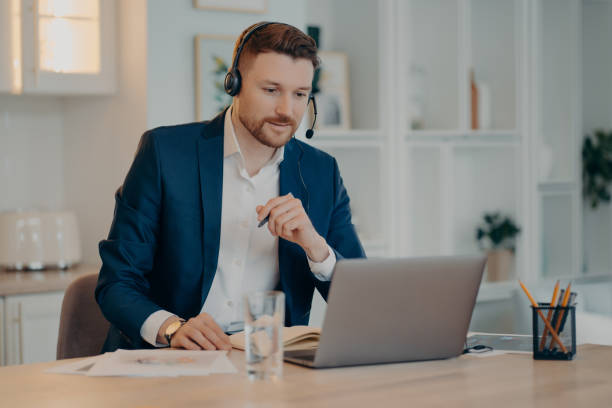istock Smiling businessman talking with his business partner while using video call on laptop 1415370341