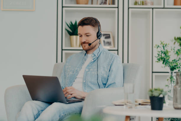 istock Happy young man sitting and typing on laptop 1415370386
