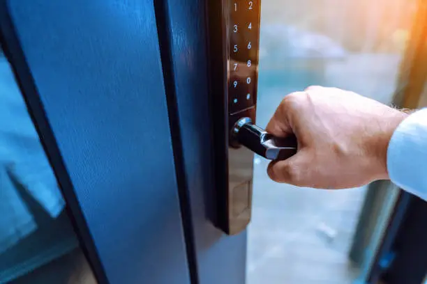 Photo of Male hand holding a handle of key free smart lock. Keyless access to home or hotel.