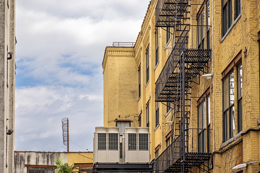 Long Island City, Queens, New York, NY, USA - July 7th 2022: Yellow painted brick building with fire escape