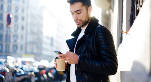 istock Young ethnic man using smartphone on street 1415372622