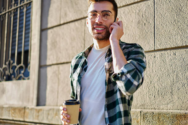 istock Content young man with takeaway coffee talking on smartphone on sunny day 1415372651