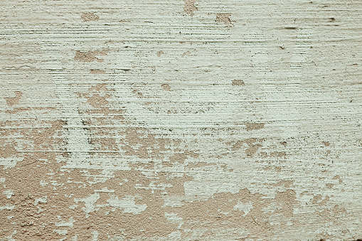 Beige paint brushed wall background with detailed texture. A concrete plastered surface with cracks and brush strokes. Minimal urban photo. Easily add depth and organic texture to your designs.