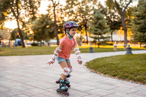 Young girl roller skating in the park, on a sunny day.