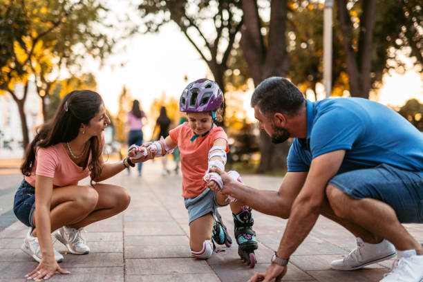 istock Young Father And Mother Teaching Their Daughter How To Roller Skate 1415377418