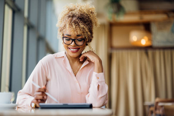 istock Beautiful Woman Working as a Digital Nomad Using Her Tablet at the Cafe 1415377641