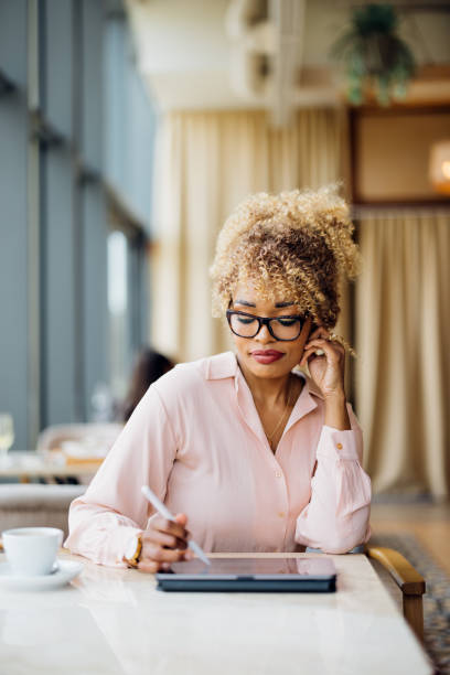 istock Beautiful Woman Working as a Digital Nomad Using Her Tablet at the Cafe 1415377644