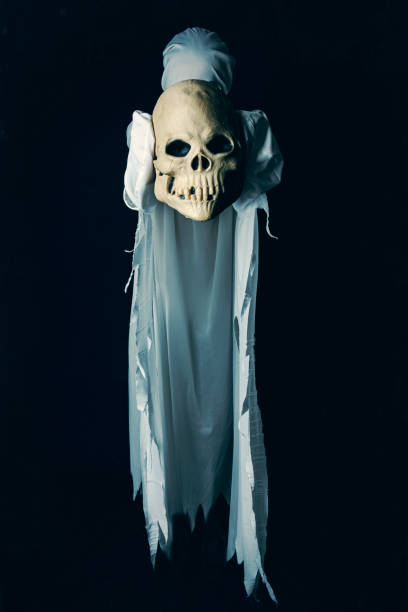 istock Halloween Ghost Holding Skull Out to Camera 1415378095