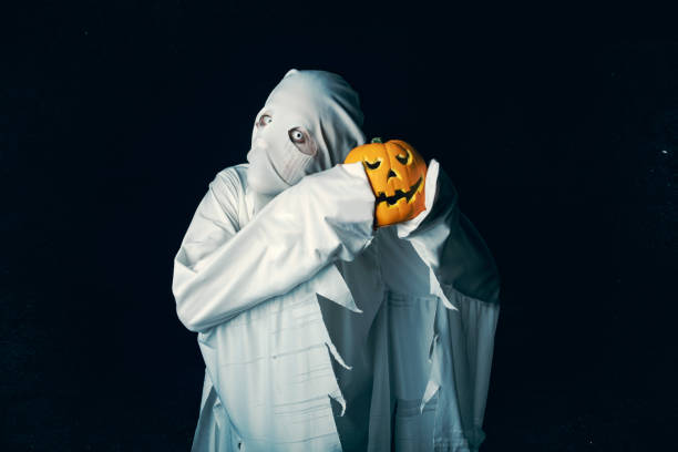 istock Spooky Halloween Ghost Holding Pumpkin 1415378169