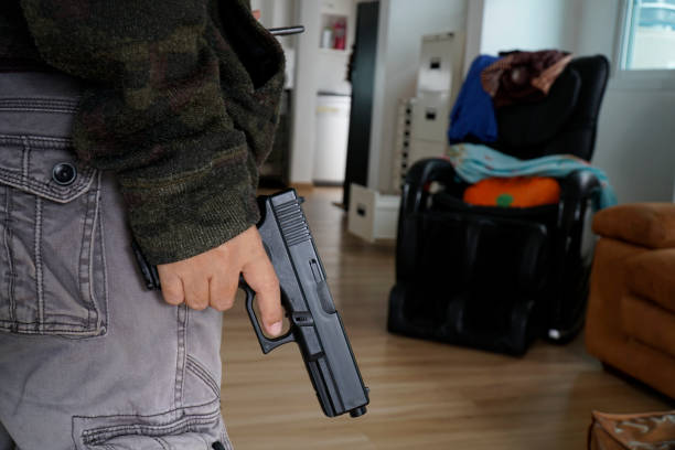 istock A woman hides a pistol behind her back. 1415380497