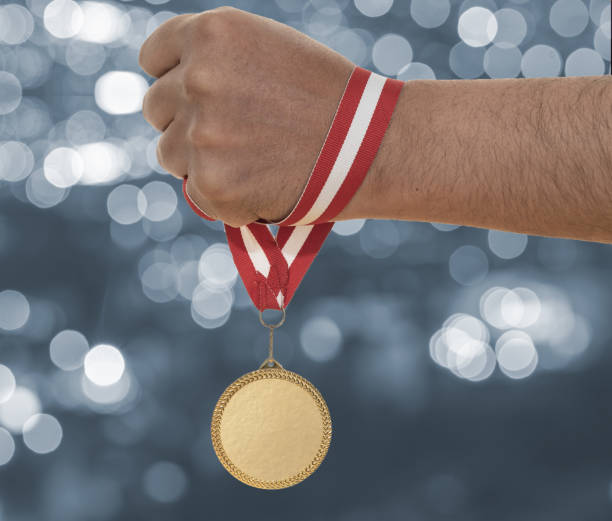 istock Man raising hand and holding gold medal. 1415381375
