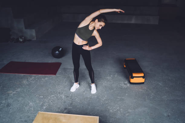 istock Athletic fitness woman doing side bend stretches 1415381502