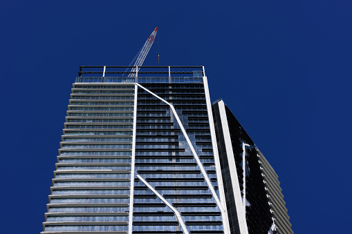Tall office building nearing completion, with deep blue sky and a crane.