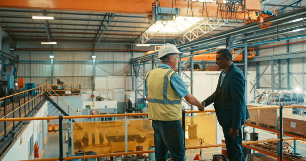 Business people at an industrial workshop handshake at a factory. Successful business man congratulating contractor for excellent work on maintenance, development and management. stock photo