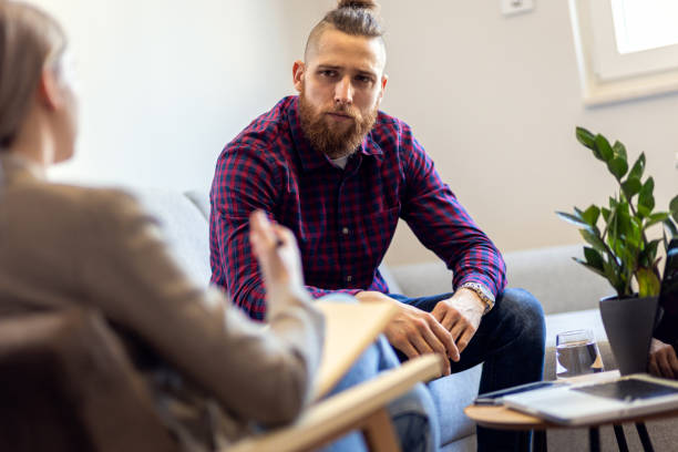istock Young man talking to female psychologist during session. 1415382996