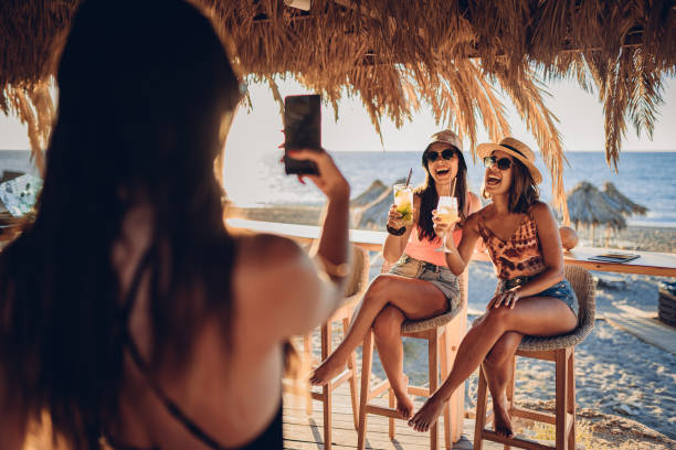 Best friends in beach bar taking selfies with mobile phone stock photo