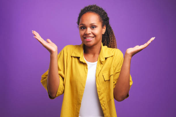 young doubting african american woman smiling, shrugs shoulders and raises palms - blank expression head and shoulders horizontal studio shot imagens e fotografias de stock