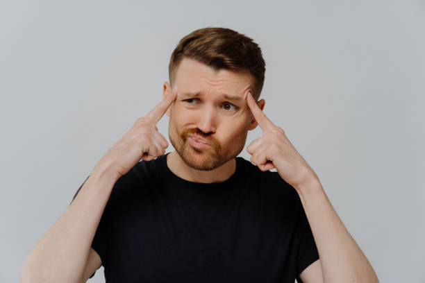istock Concerned man holding fingers on temples and thinking 1415386589