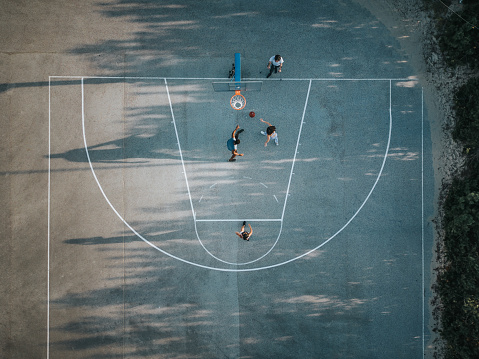 Drone point of view of basketball court with people playing on it.