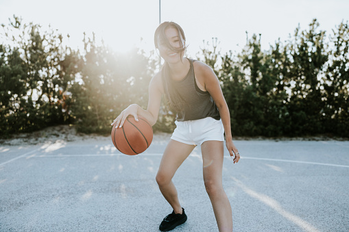 Young Japanese woman, focused on game of basketball.