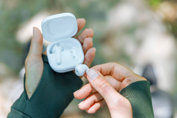 istock Woman hand taking out a white wireless earbud from her charging box. Female hands touching a portable headphones 1415389194