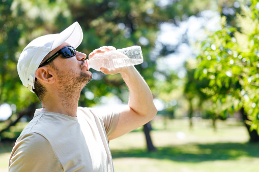 Sporty young man wearing sunglasses drinking water