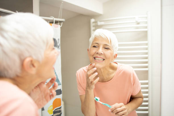istock Senior woman brushing her teeth 1415389406