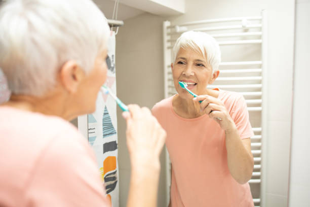 istock Senior woman brushing her teeth 1415389463