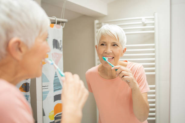 istock Senior woman brushing her teeth 1415389477