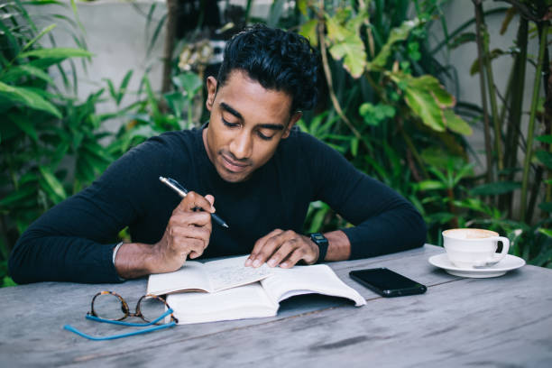 istock Concentrated ethnic male writing in notepad 1415390380