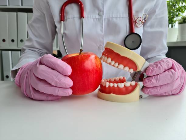 istock Dentist holding artificial jaw and apple closeup 1415392879