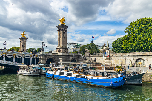 Green barge moored to the banks of the Seine river in Paris, France on a summer day