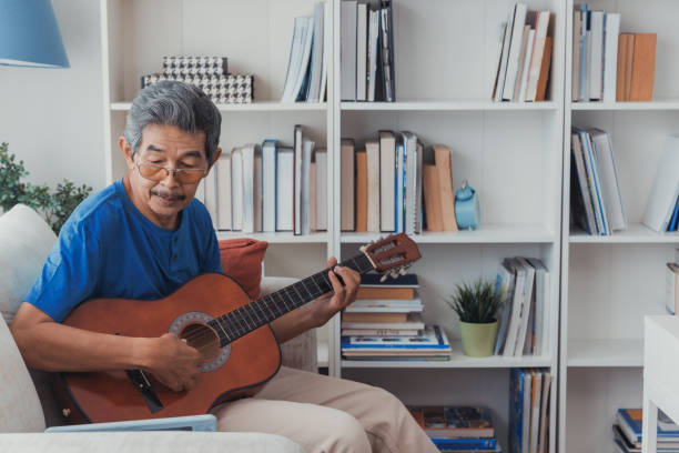 istock Senior man playing guitar in living room. 1415401573