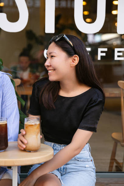 istock Cheerful asian young woman drinking cold coffee while sitting in cafe 1415402573