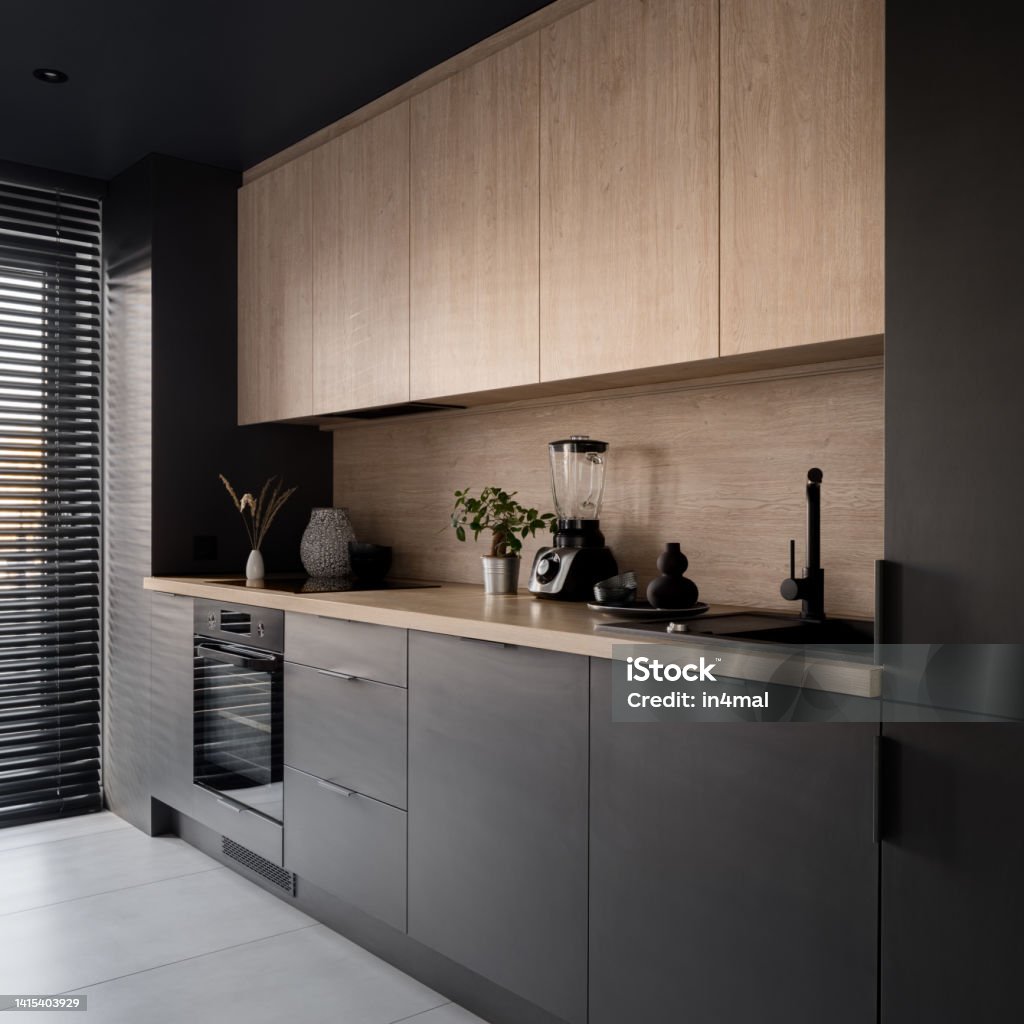 Small and modern kitchen with wooden details Small and modern kitchen with wooden and black cupboards, wooden backsplash and countertop Kitchen Stock Photo