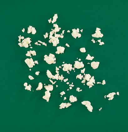 Crumbled cheese on green background