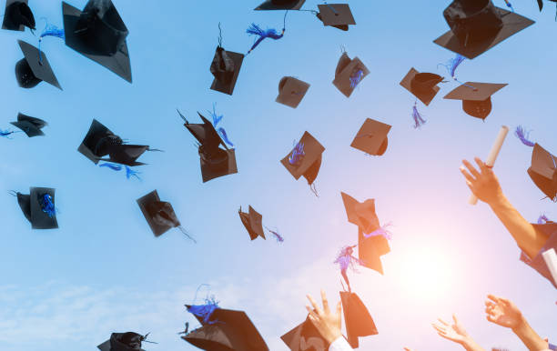 istock Graduating students hands throwing graduation caps in the air 1415405809