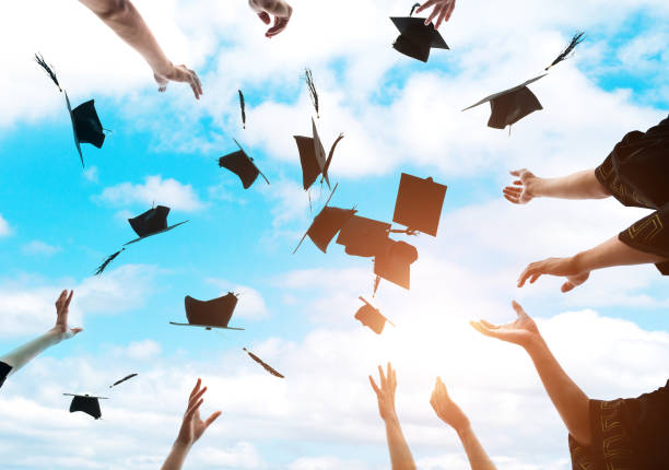istock Graduating students hands throwing graduation caps in the air 1415405818