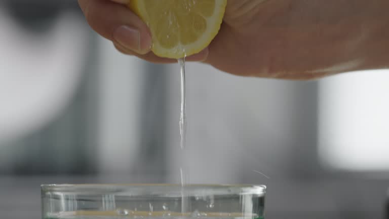 Squeezing a lemon into a glass of water