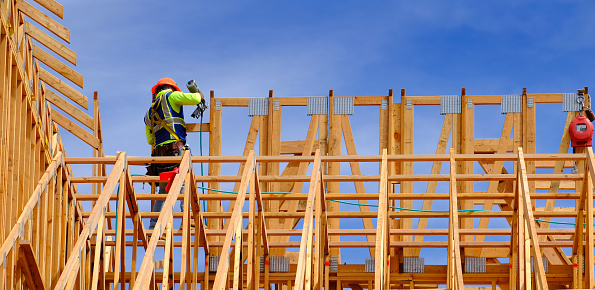 Construction workers working on new home or restidential building with wooden beams framed and sky