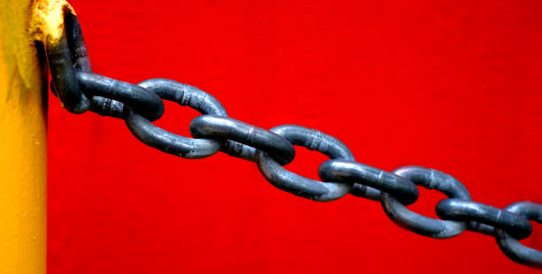 istock Chain Hanging from Yellow Pole with Red Wall Background 1415408569