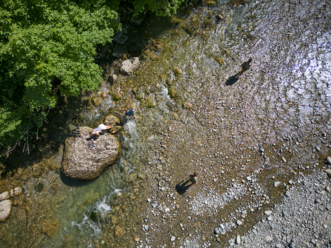 Mother and three teenage kids are hiking in the Alps - Vorarlberg, Austria. They are playing in the river. Aerial drone view.\nDJI Mini 3 Pro.