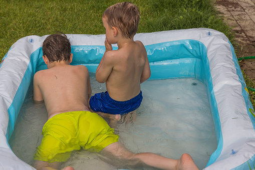 Close up view of two young boys in inflatable pool on backyard on hot summer day. Sweden.