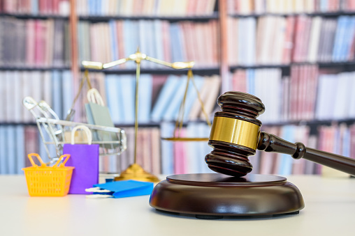 Consumer protection law, rights and guarantees, justice concept : Judge gavel, balance scale, bags, a shopping cart, depicting a safeguard designed to protect buyers from fraudulent business practices.